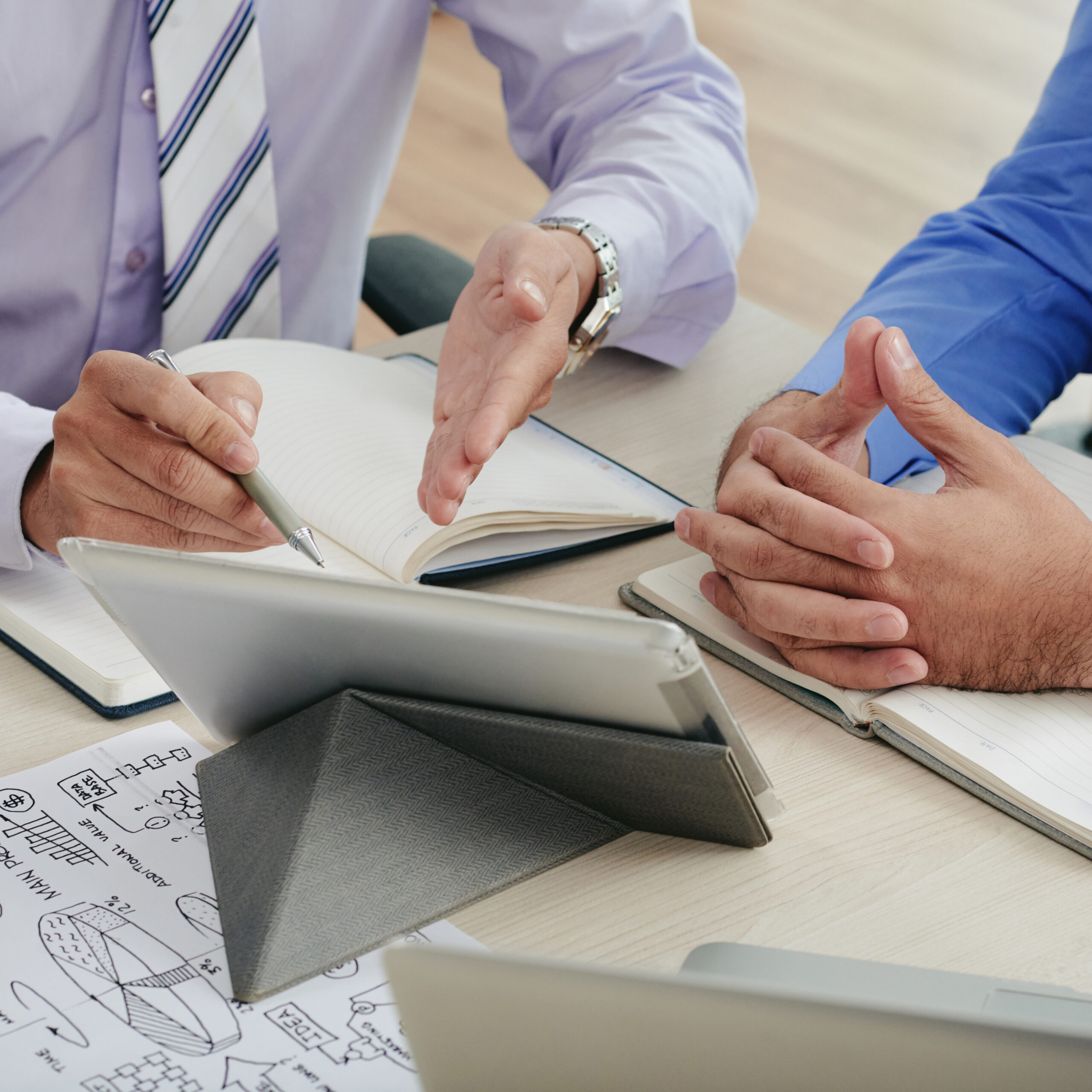 Close-up image of coworkers discussing data on tablet computer screen
